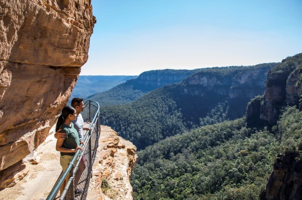 A couple enjoying the views from the Wentworth Falls Track, overlooking the mountains.