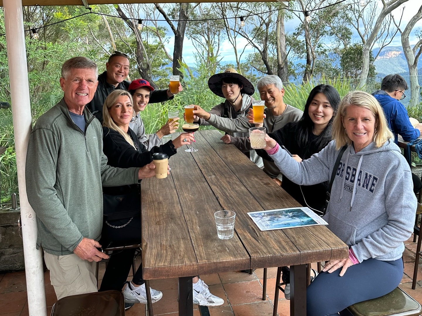Visitors enjoying drinks at Echo Point, with a stunning view of the Three Sisters rock formation and the Blue Mountains in the background.