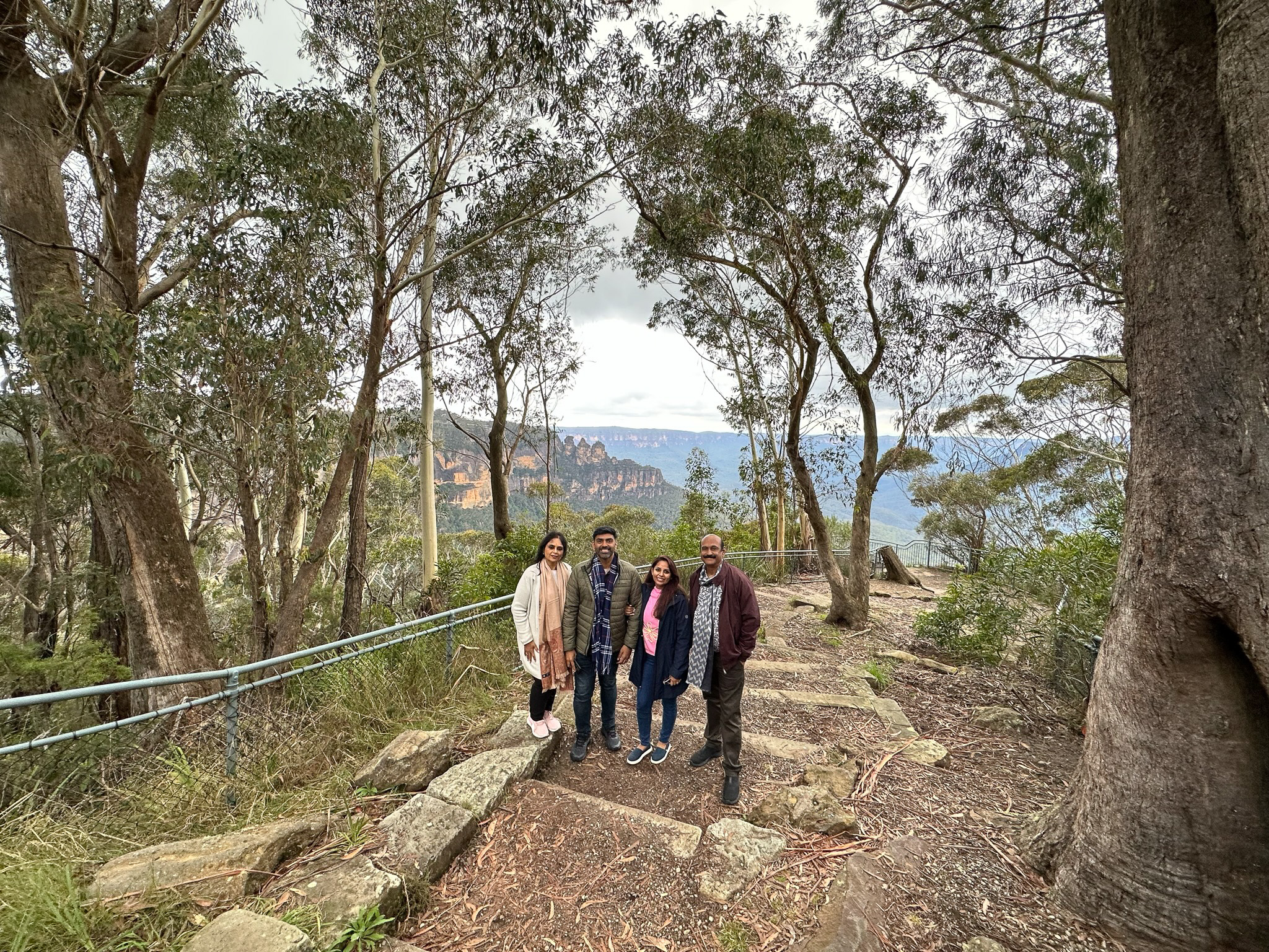A group of visitors enjoying the stunning panoramic views at Eagle Hawk Lookout, Katoomba, with vast landscapes and rugged cliffs in the background.
